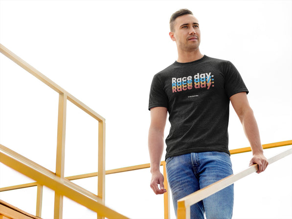 Man wearing a black t-shirt with colorful text, standing on a yellow railing.