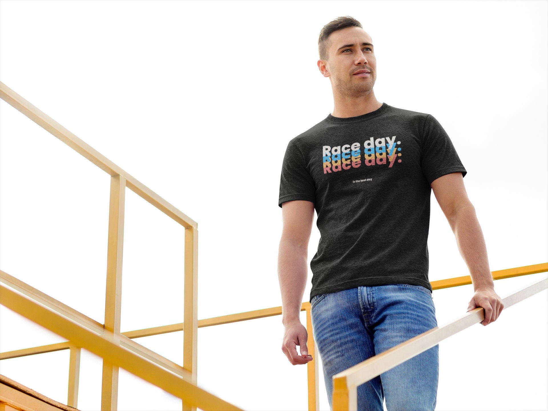 Man wearing a black t-shirt with colorful text, standing on a yellow railing.