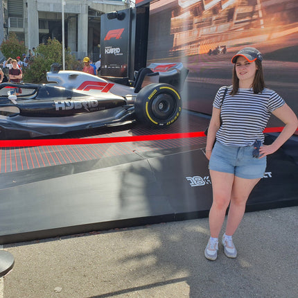Woman standing next to a Formula 1 car display at an event