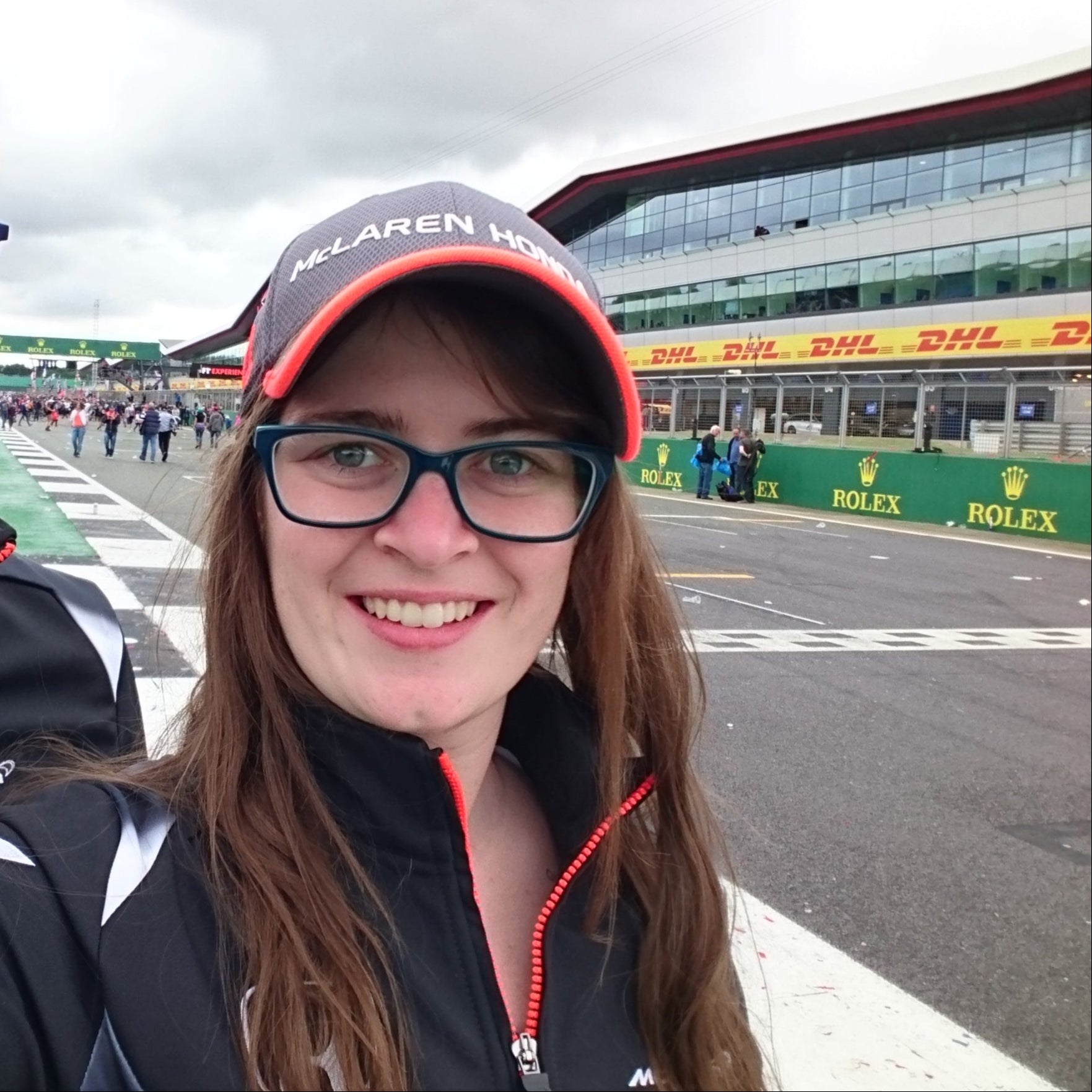 Two people taking a selfie on a race track with racing-themed clothing and branding.