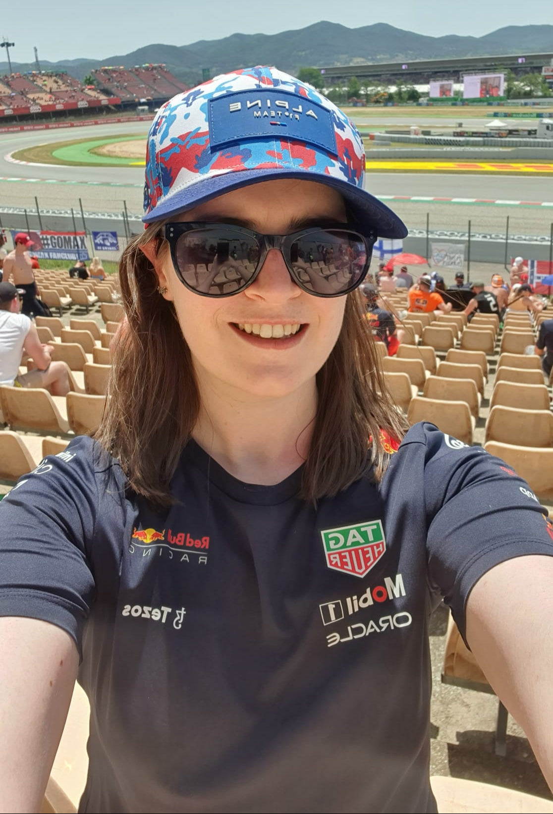 Person wearing a branded t-shirt and cap at a race track.