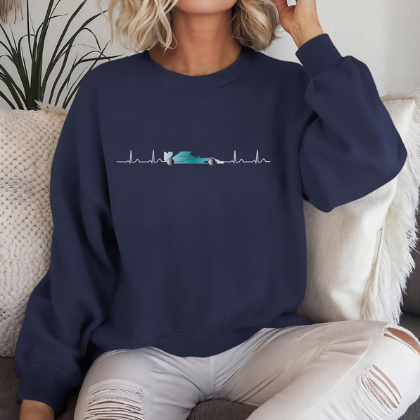 Person wearing a navy blue sweatshirt with a f1 car graphic design sitting on a white couch.
