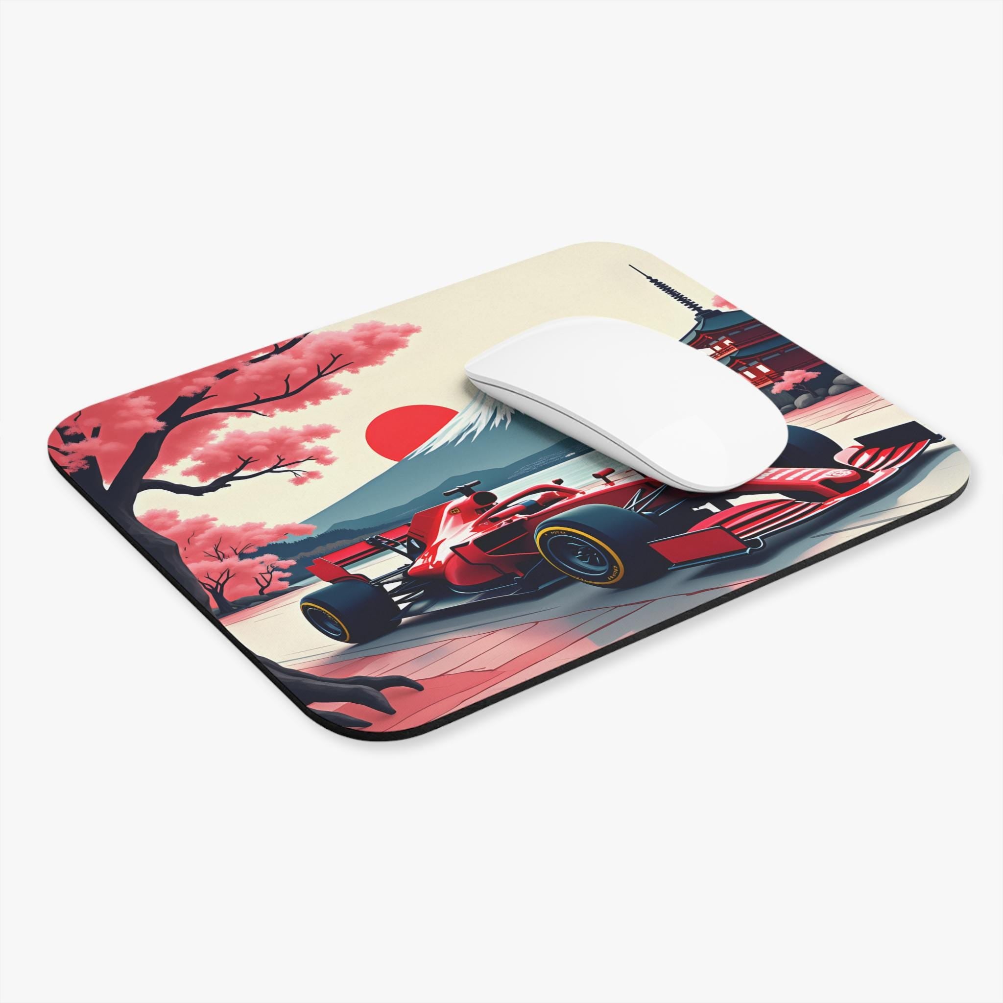A red race car on a mouse pad with a Japanese theme. The mouse pad has a red sun, a mountain, cherry blossoms, and a temple. A white computer mouse is on the mouse pad.
